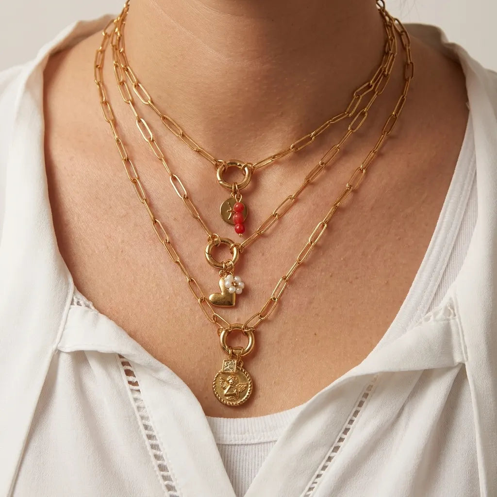 Chain necklaces with various charms on a person wearing a white shirt