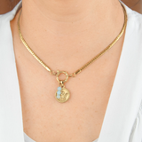 Gold necklace with two charms on a person wearing a white shirt