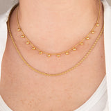 Golden drops set on a person's neck with a neutral background