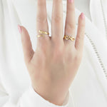 Hand wearing two gold rings on a white background