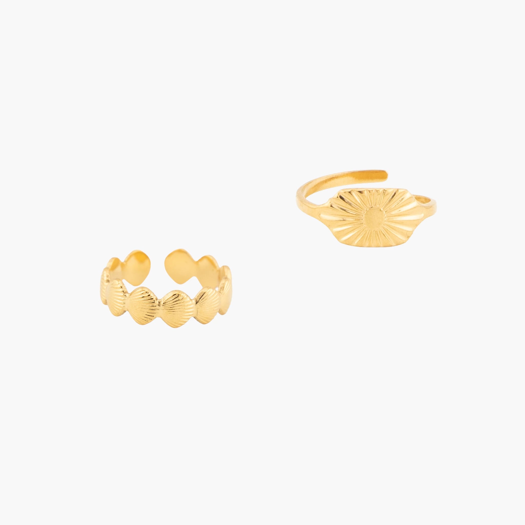 Two gold rings with textured designs on a white background