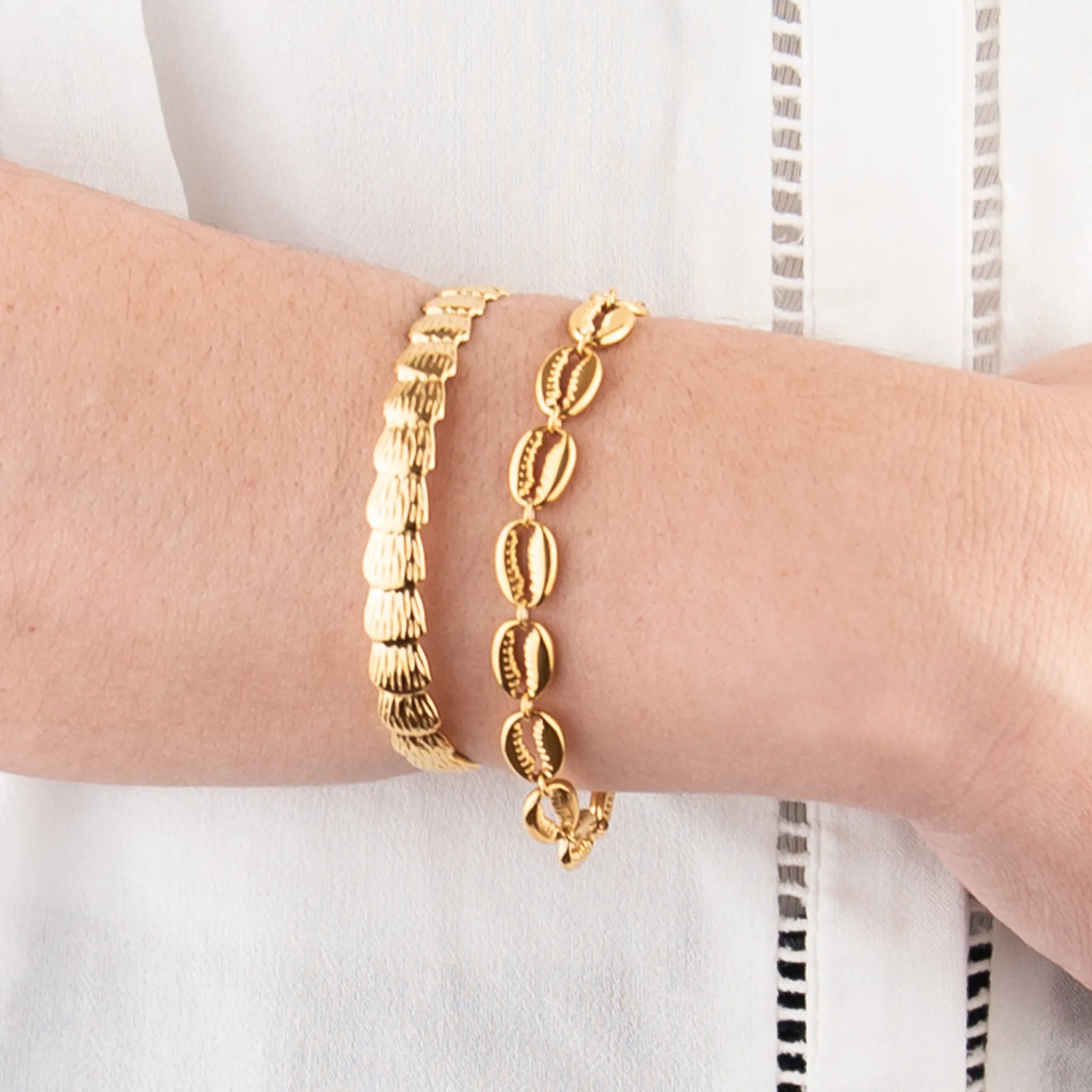 Golden shells set on a person's wrist with a white background