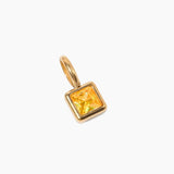 November birthstone charm, golden pendant with a square yellow gemstone on a white background