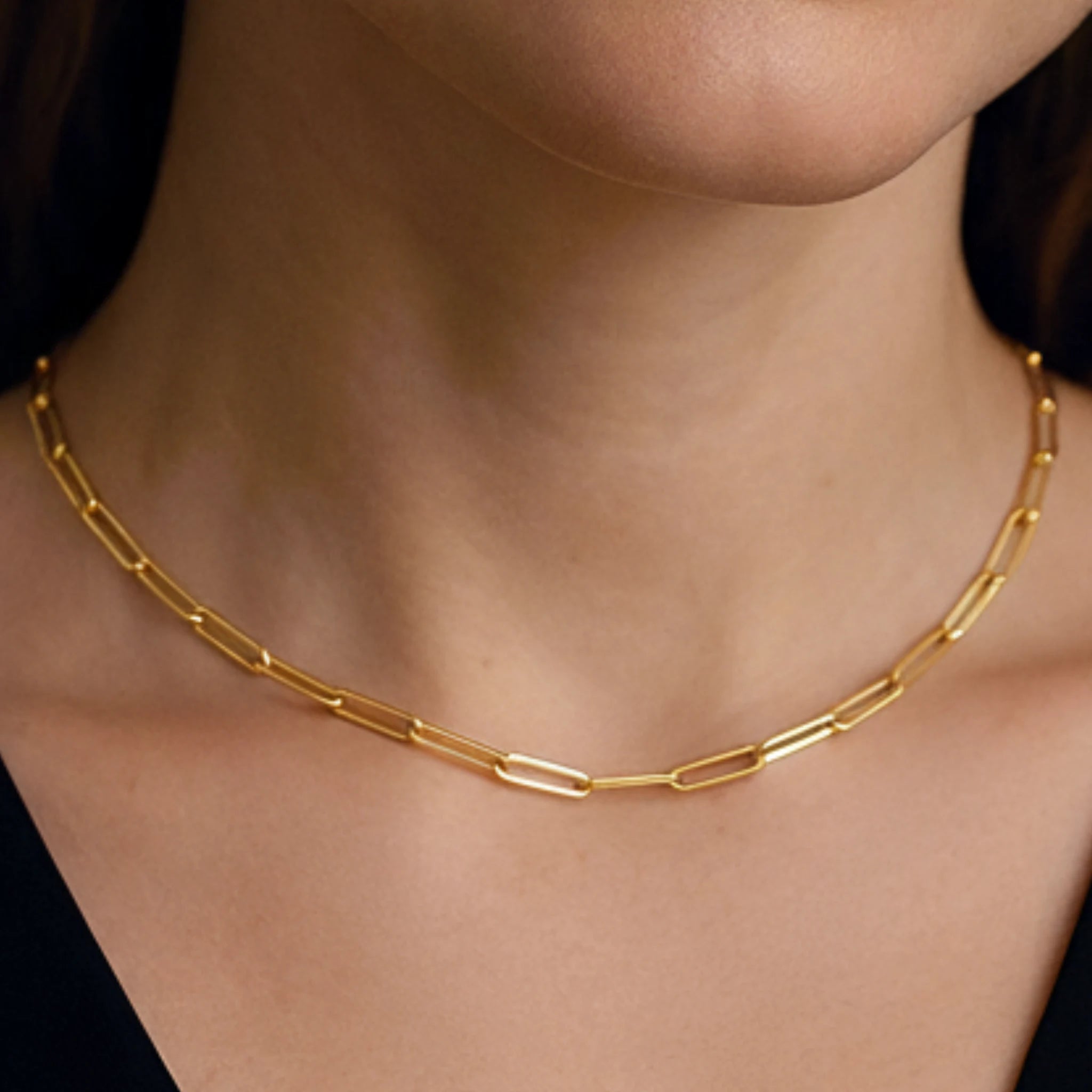Paperclip chain choker worn by a person on a black background