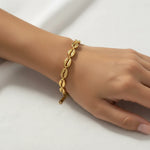 Gold cowrie shell bracelet on a wrist against a white background
