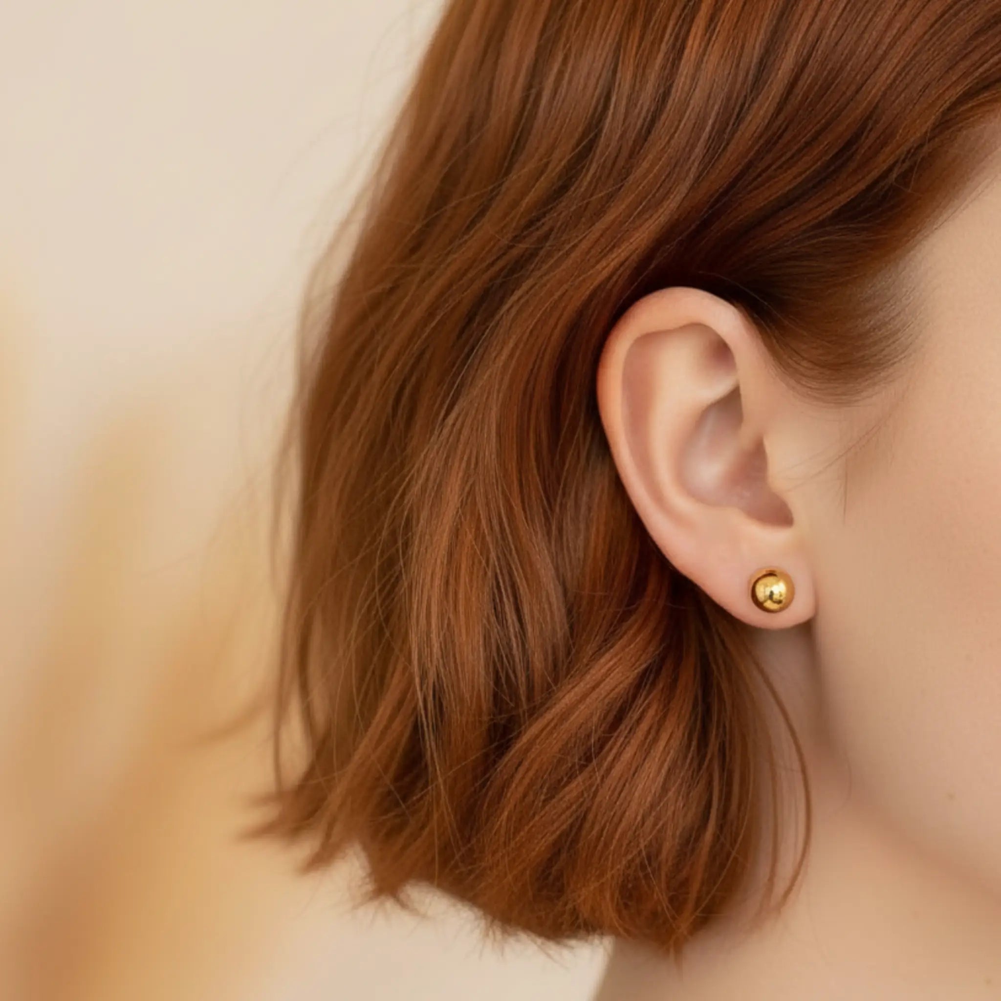 Close-up of an ear wearing a gold ball earring