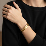 A woman wearing a minimalist gold cuff bracelet and a black shirt