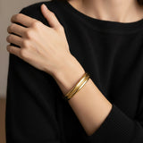 A woman wearing a minimalist gold cuff bracelet and a black shirt