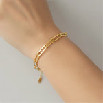 Gold chain bracelet on a wrist against a neutral background