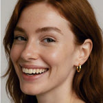 Woman wearing a gold octagon hoops earring with a neutral background