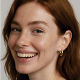 Woman wearing a gold octagon hoops earring with a neutral background