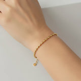 Gold oval bead bracelet on a wrist against a neutral background