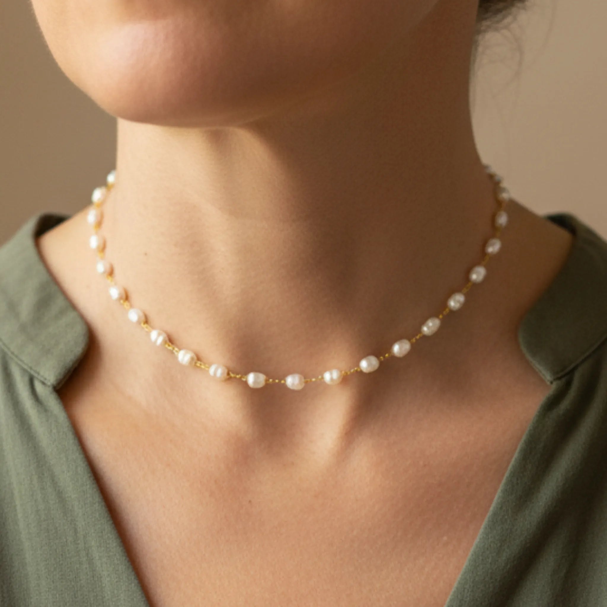 A woman wearing a pearl choker and a green shirt