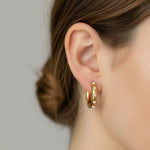 Gold pearl detail hoops worn by a person against a neutral background