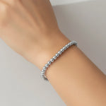 Silver beaded bracelet on a wrist against a neutral background