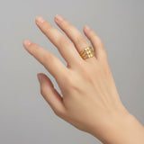 Hand wearing a gold triple layer ring on a plain background